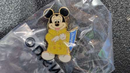 1st Disneyland Former Cast Member Association with Mickey in a yellow coat holding a blue pennant
